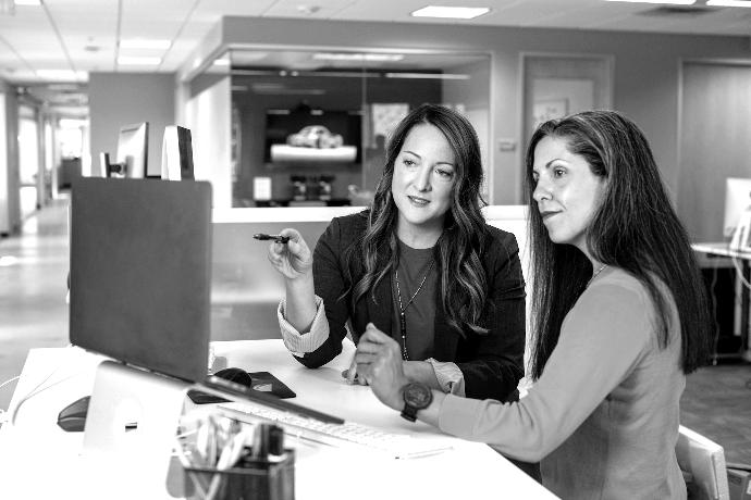 two women sitting at a table looking at a computer screen